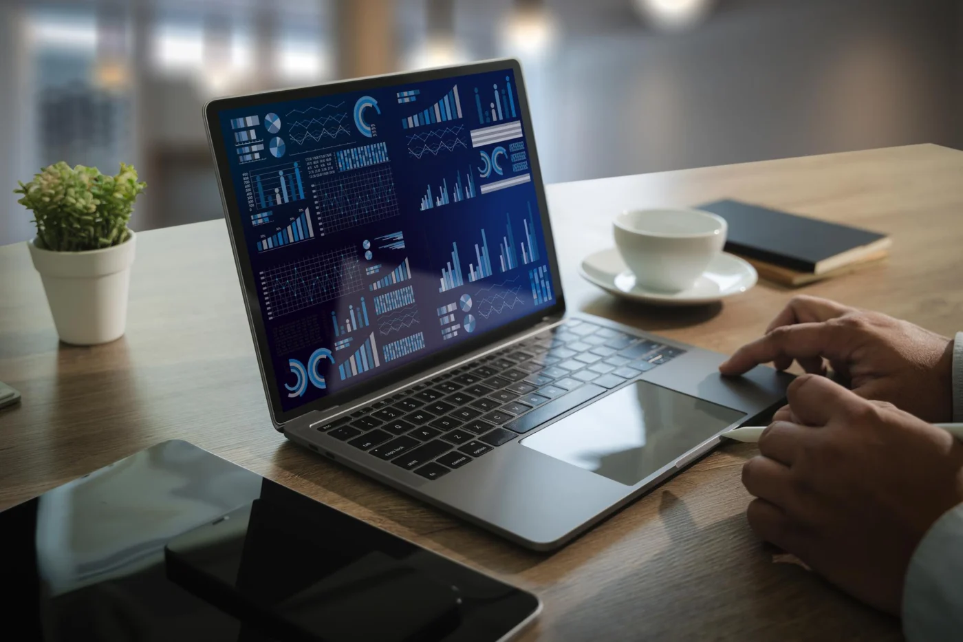 A laptop showing financial charts and a dashboard on a desk
