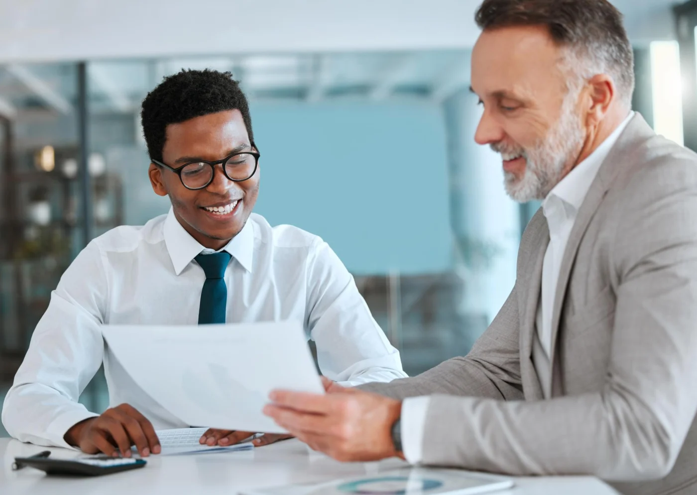 A welcoming accountant greeting a new client across a desk in a modern Isle of Man office