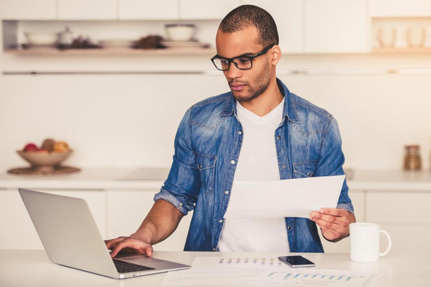 A business owner reviewing paperwork at a laptop