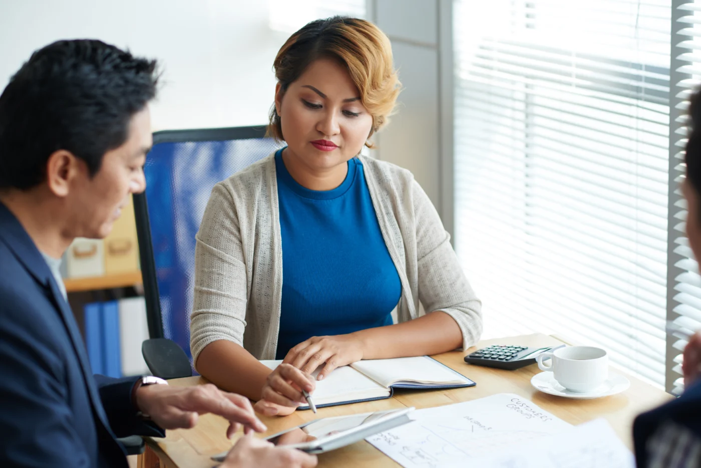 Two professionals discussing company figures at a laptop in an office