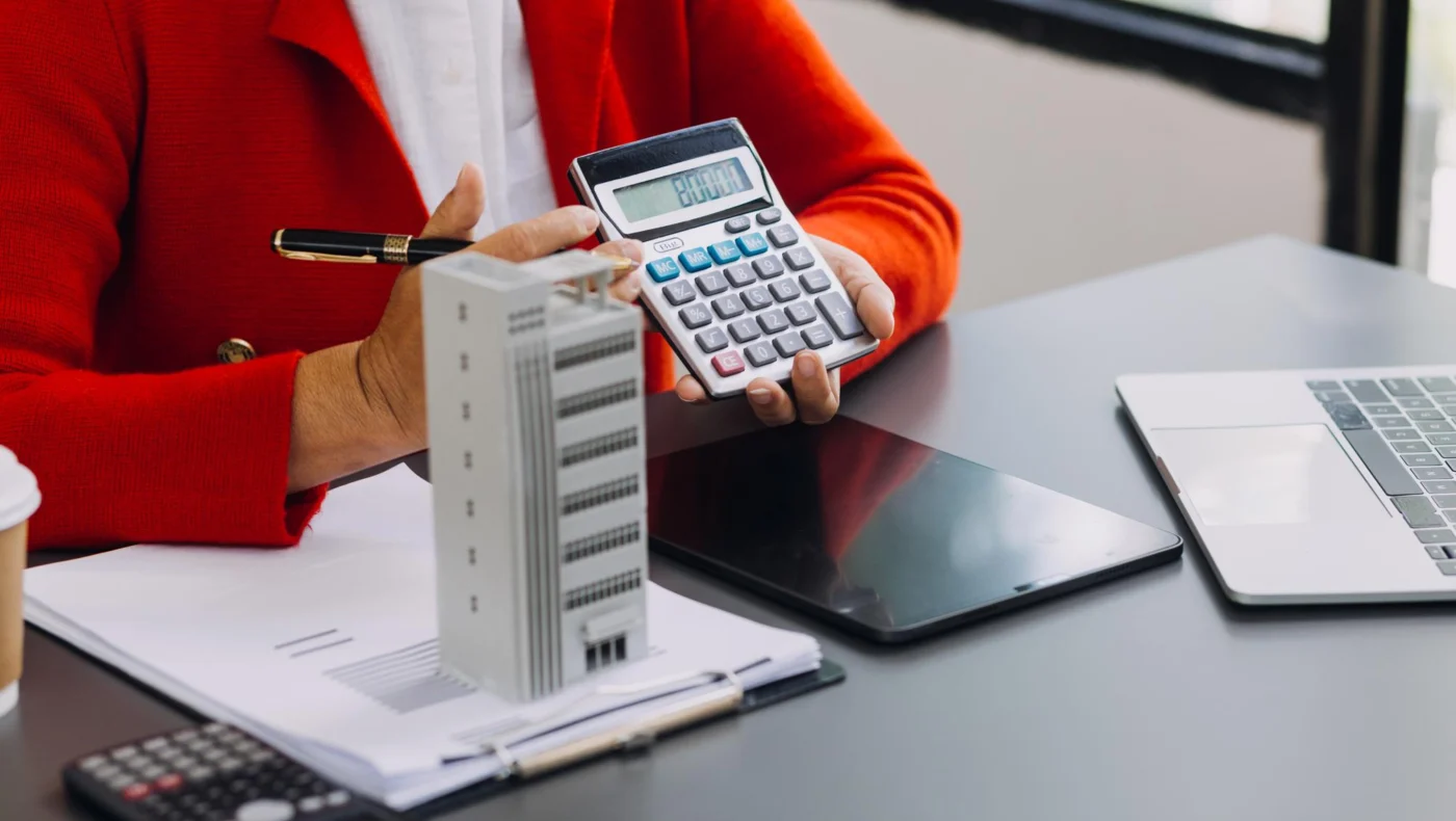 A calculator and wealth statements on a desk beside a pen