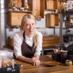 A sole-trader business owner working at the counter of their small Isle of Man shop