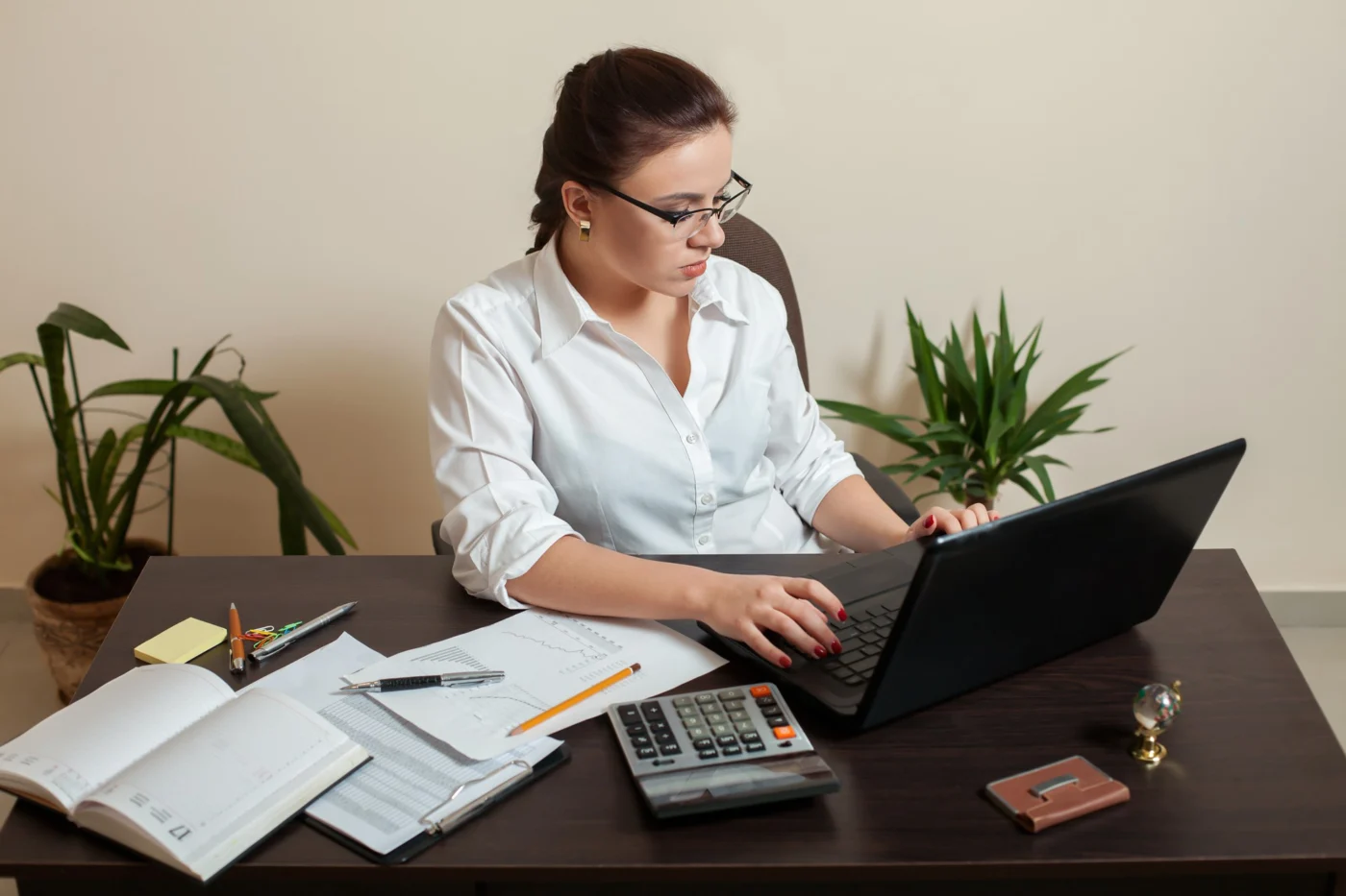 A bookkeeper reconciling accounts on a laptop at a tidy desk