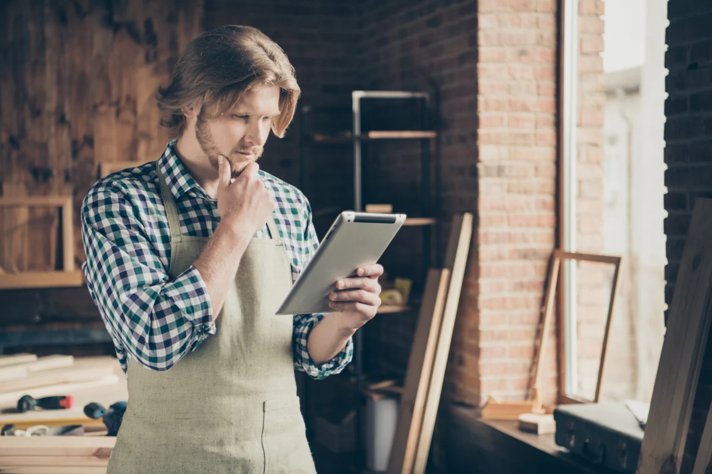 A small-business owner checking live figures on a tablet in a workshop