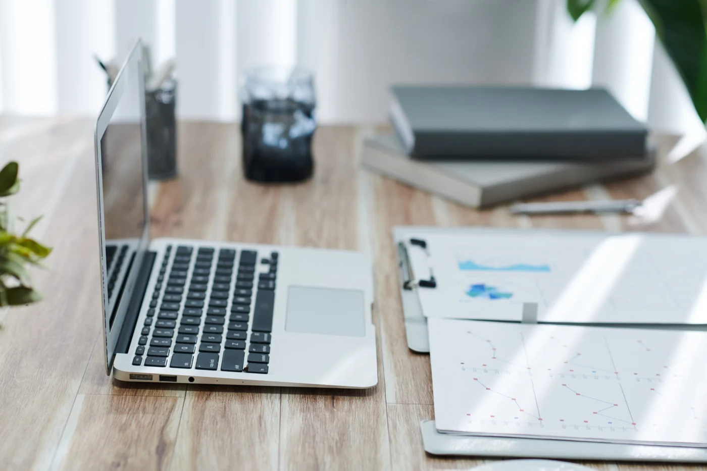 A strategy session around a boardroom table with laptops and financial reports