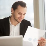 A business owner reviewing a monthly figures pack with an adviser at a desk
