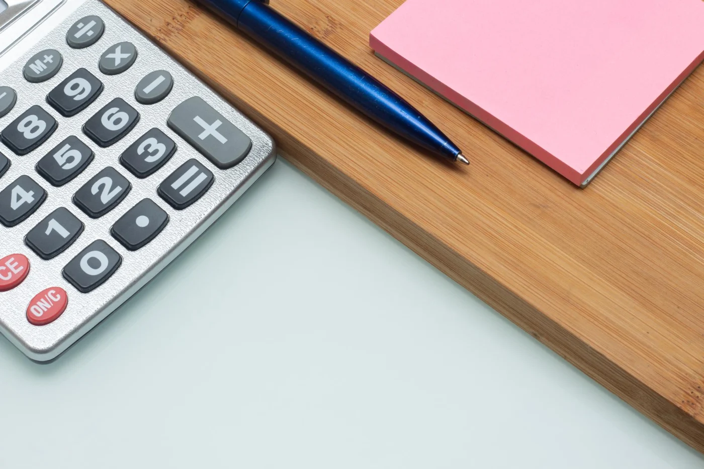 A calculator, pen and notepad on an office desk