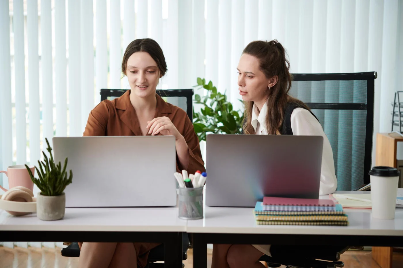 Two colleagues working together at a desk in a bright office