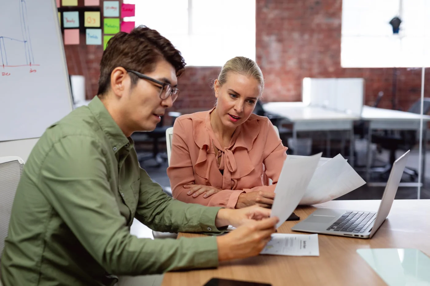 Two professionals reviewing documents in a meeting room
