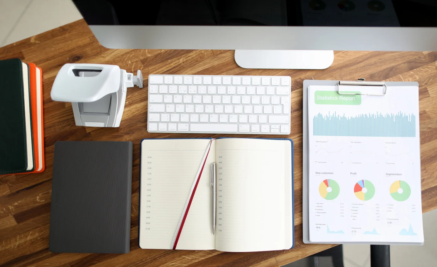 A desk with a keyboard, notebook and financial charts