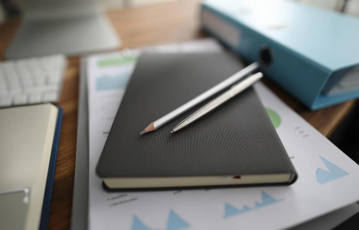 A notebook, pen and financial charts on an office desk