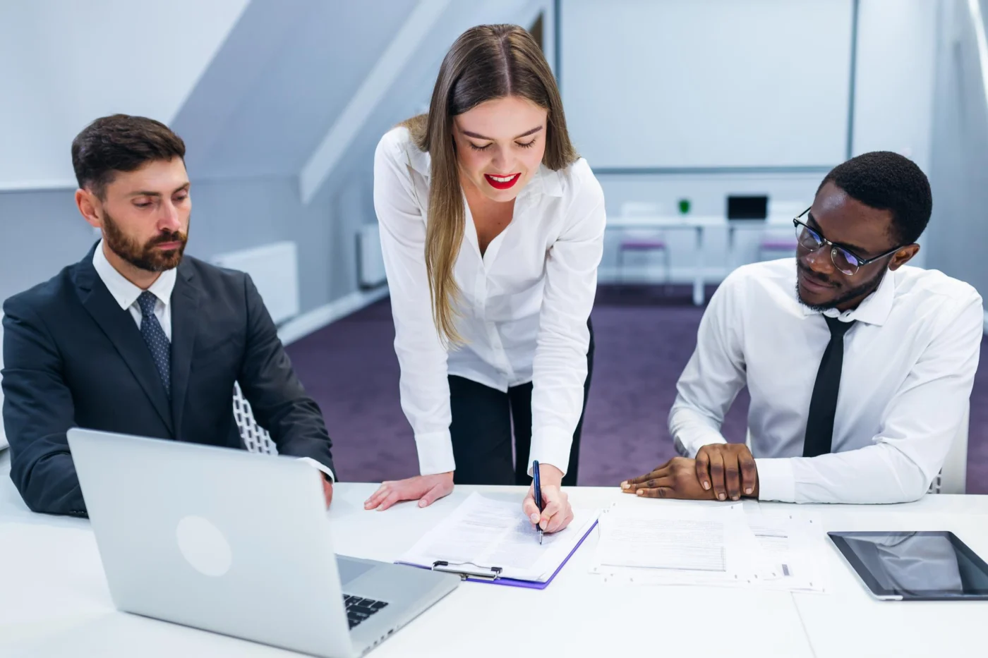 A colleague talks two business owners through a document at their desks