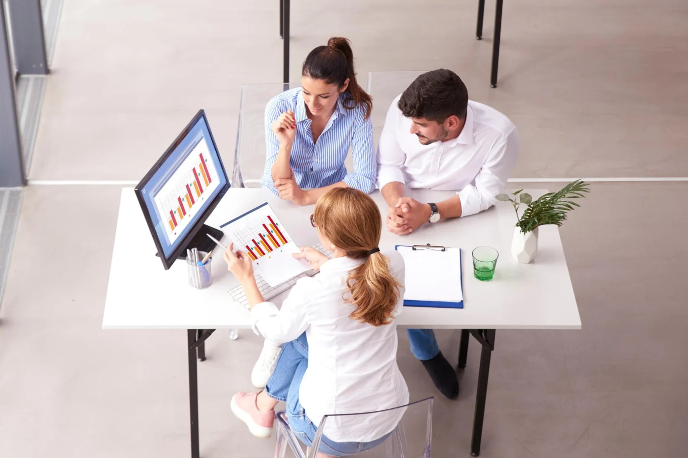 Two colleagues and an adviser review a chart and paperwork from above a desk