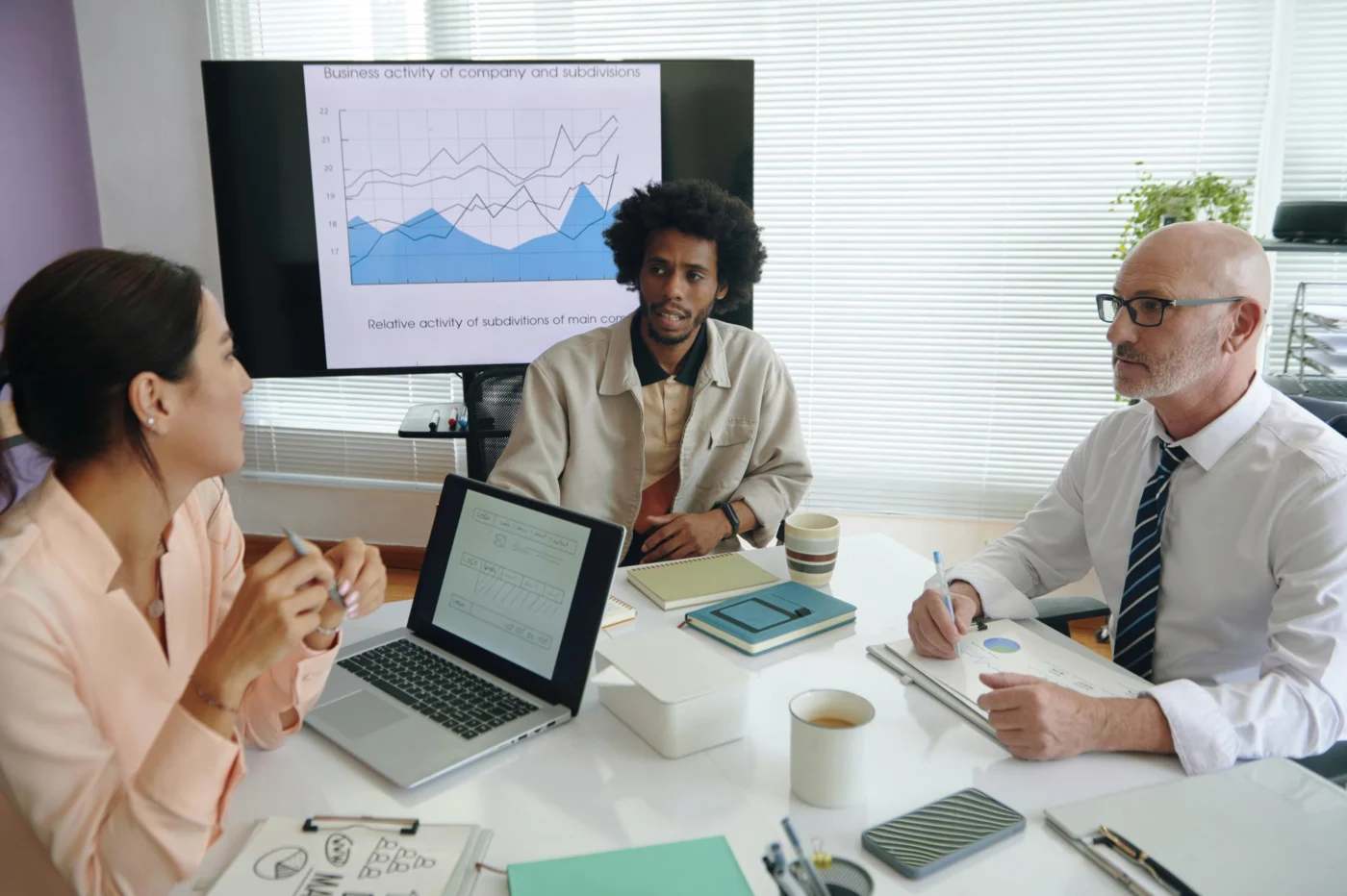 Colleagues discuss an income chart on screen in a bright office