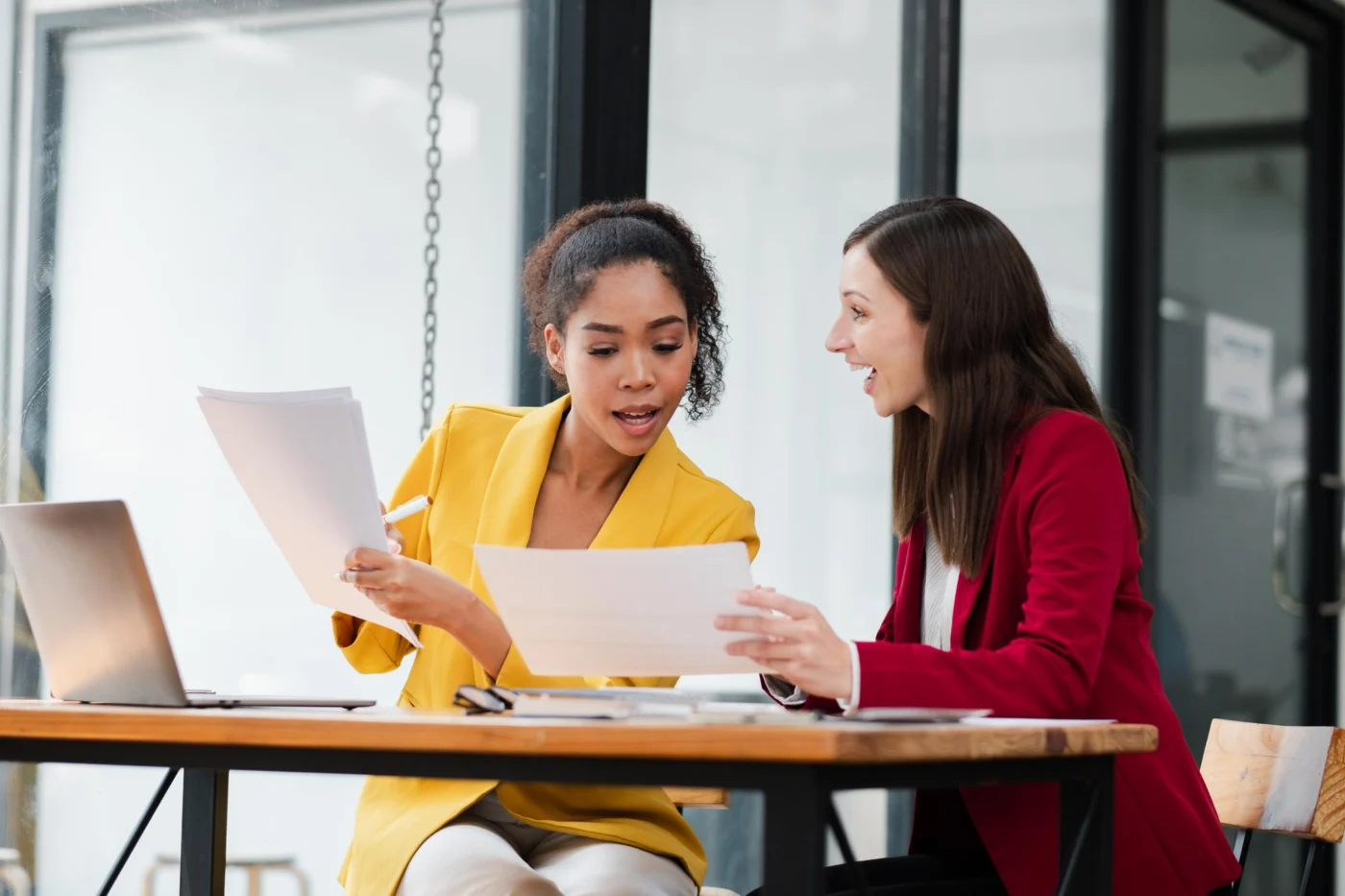 A finance manager explains a hotel invoice to a colleague at a desk