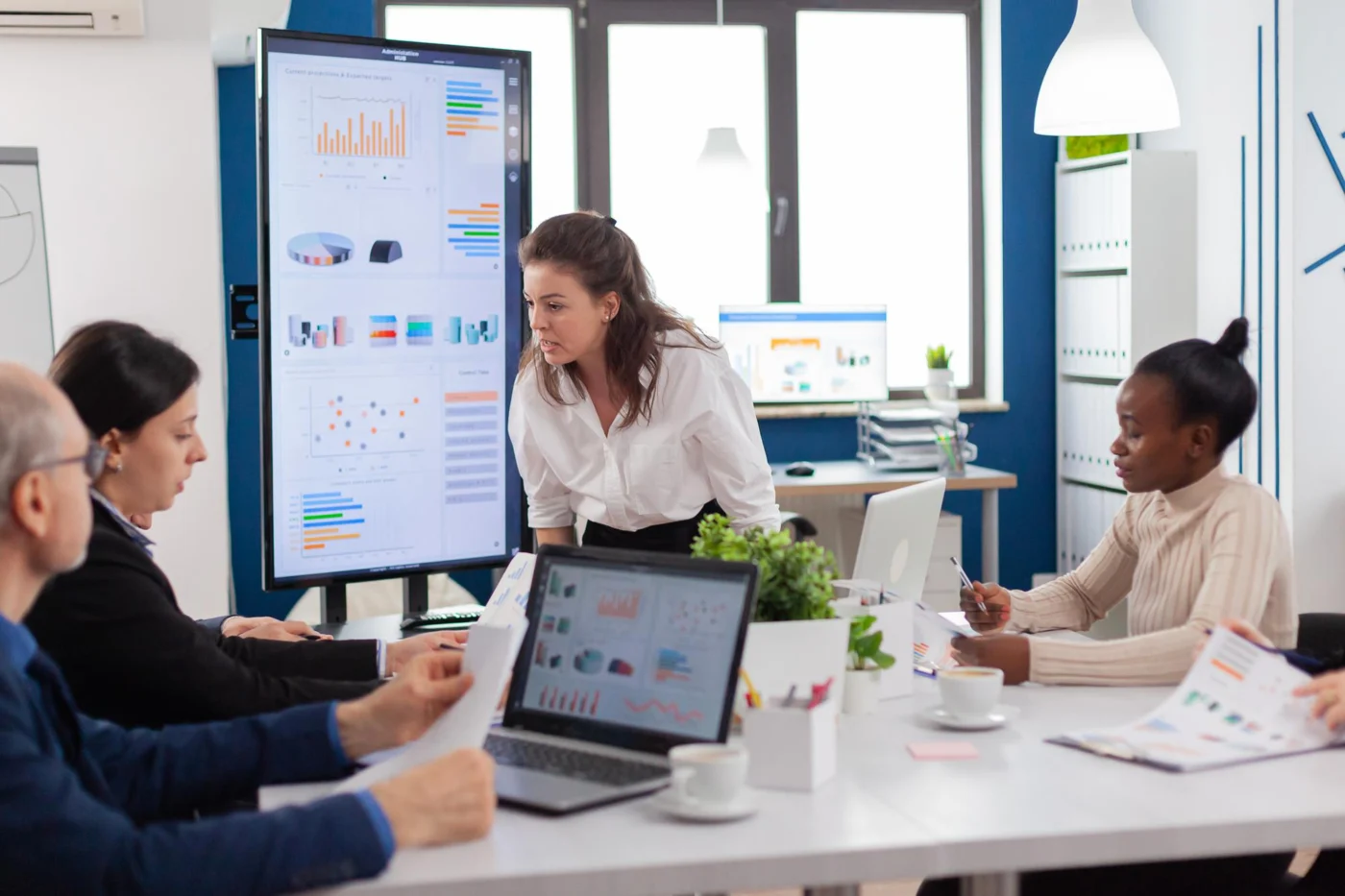 Colleagues review VAT figures on a wall screen and printed report in a meeting room