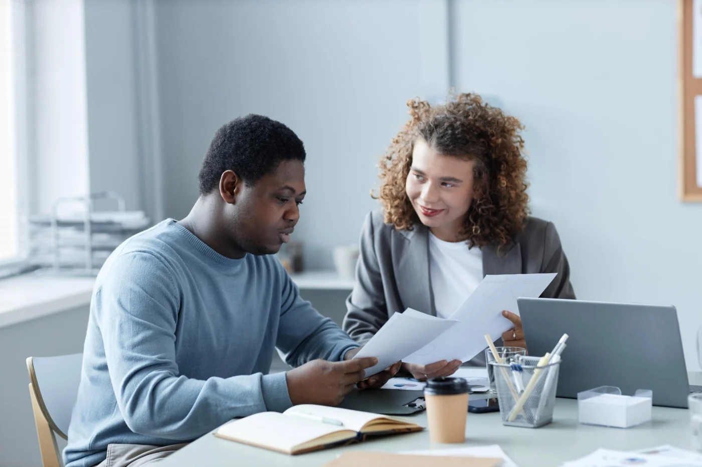 A colleague reviews a bill and a direct debit form with another at a desk