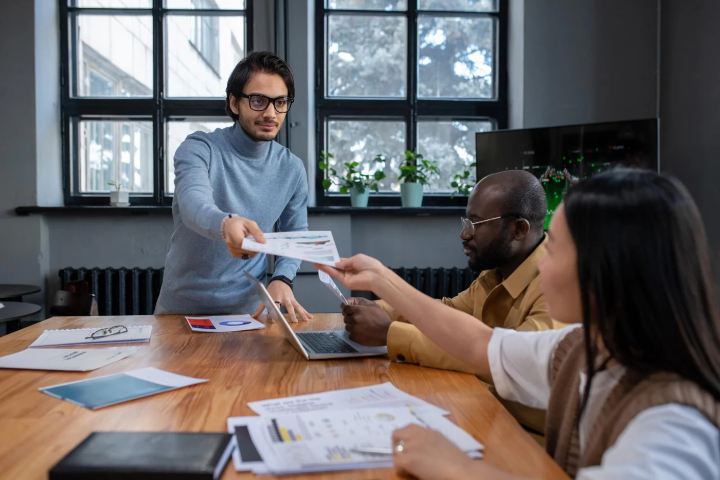 A colleague hands over a guest invoice to two others at a bright desk