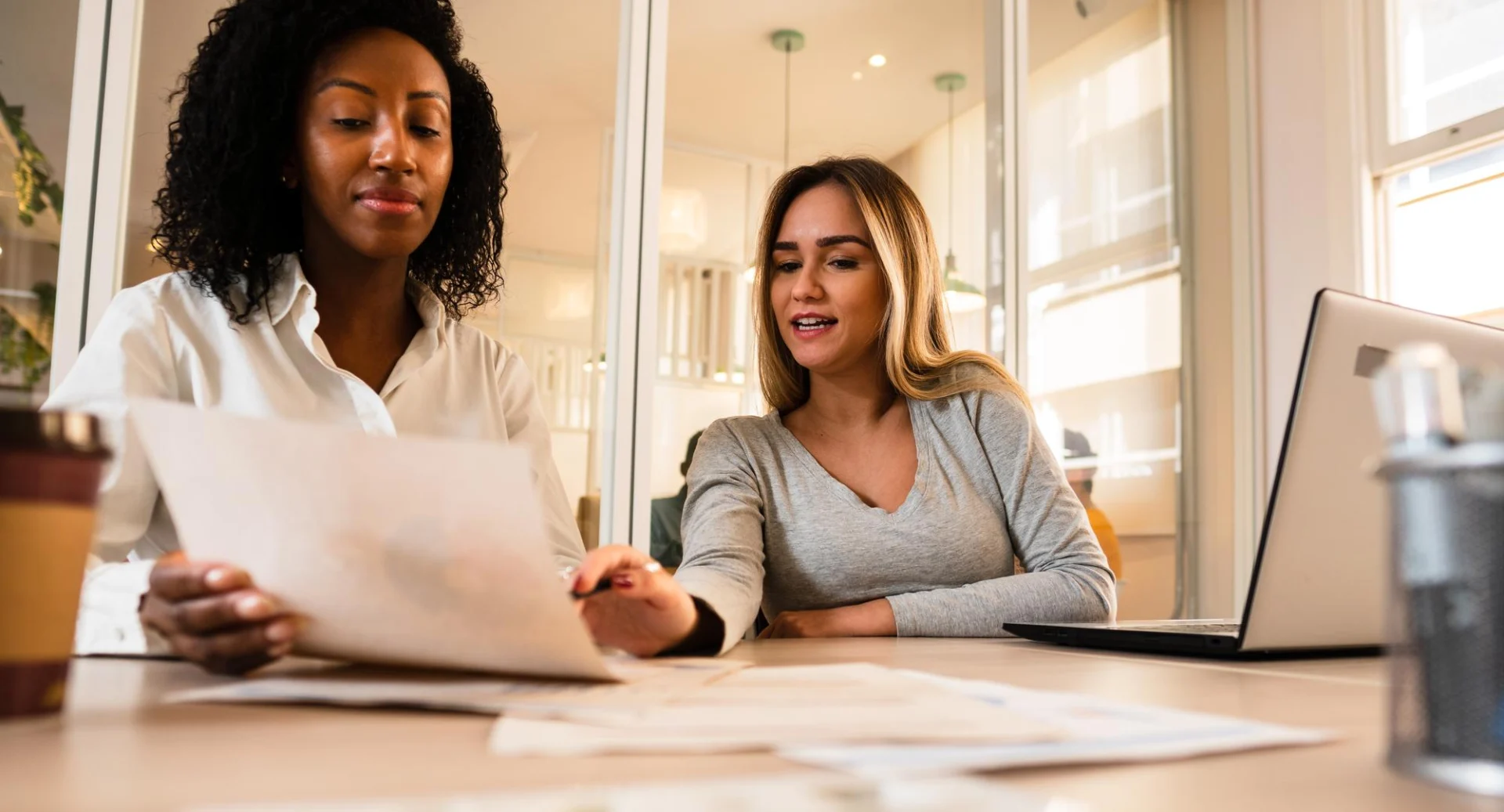 Two colleagues talk through a document together in a bright office