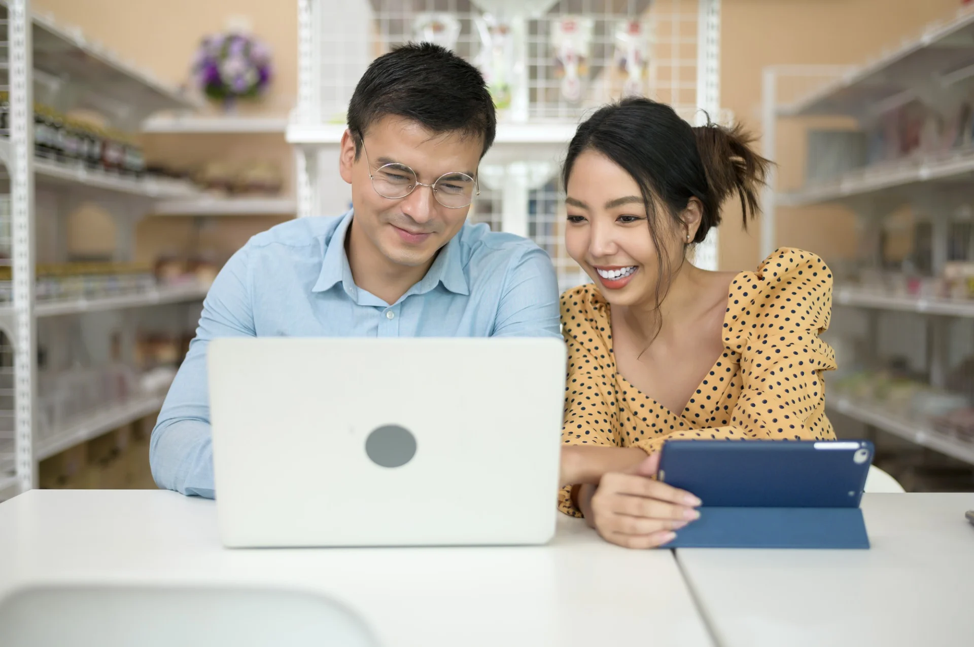 Two colleagues reviewing figures on a laptop and tablet in a bright office