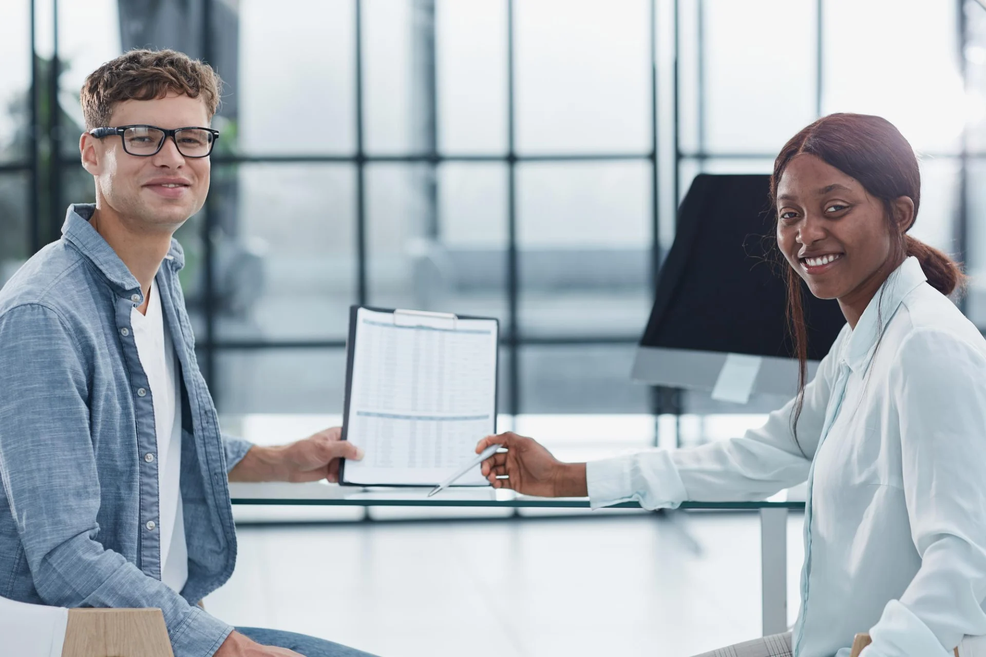 A director hands over paperwork to a colleague in a bright office