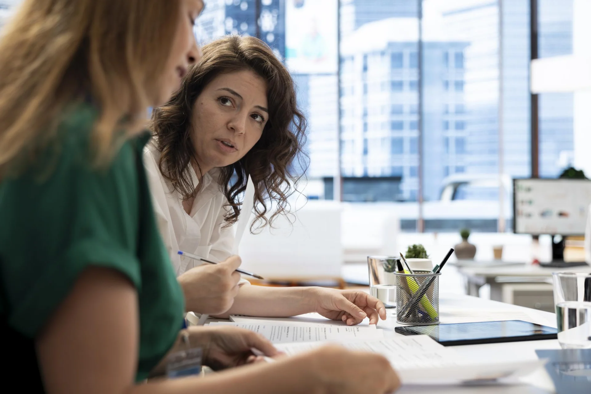 Two colleagues review staff records together in a bright office