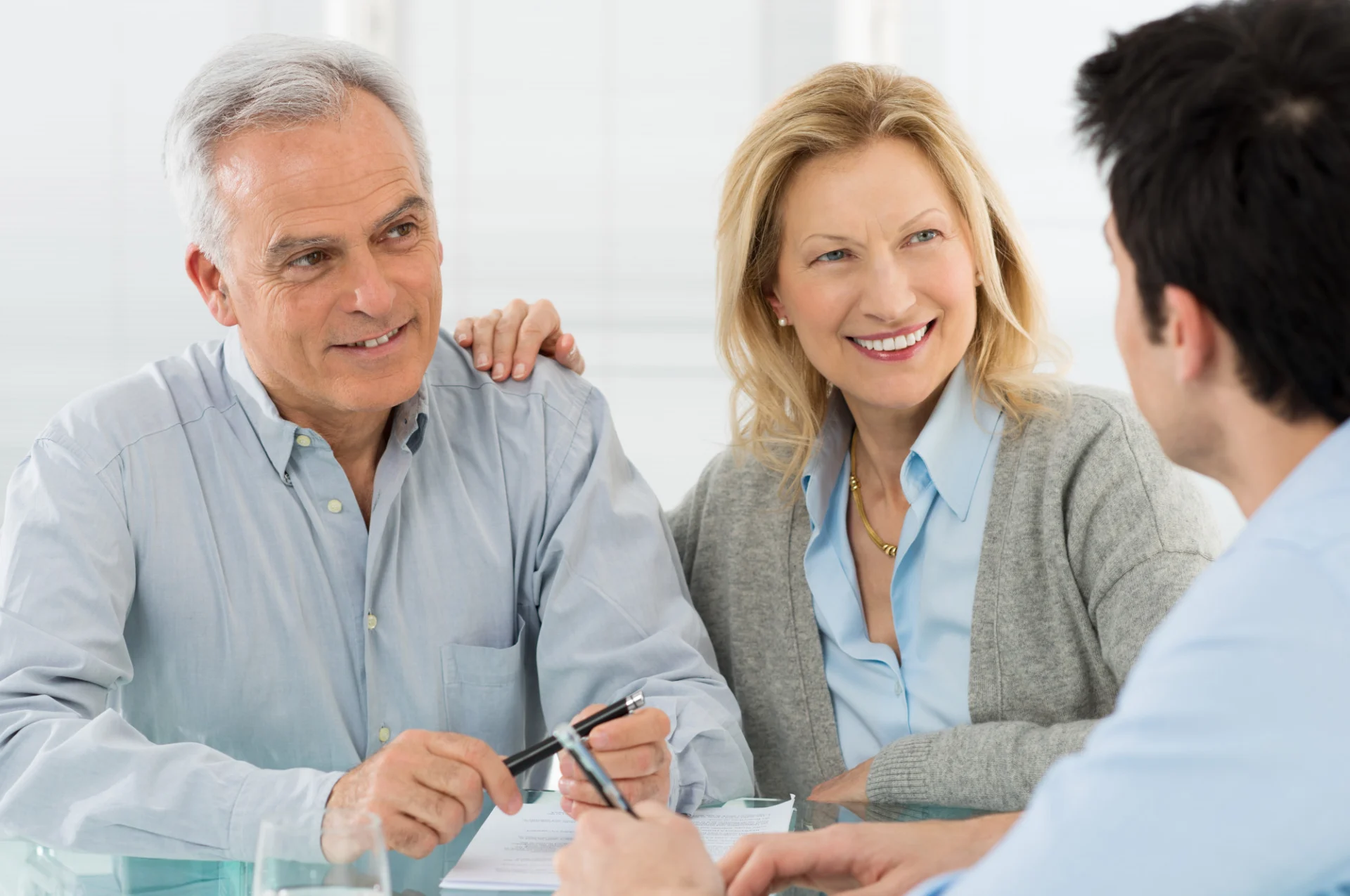 A retired couple talk through their finances with an adviser at a table
